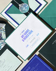 Wedding invitation set with green and blue envelopes and cards on a neutral background