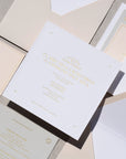 Invitation card with gold text on a gray surface