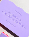 Purple card with text and a pink envelope on a light gray background