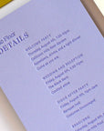 Purple event invitation card with details on a white surface