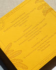 Yellow wedding invitation with engraved details on a textured surface
