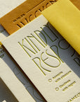 Letterpress printed card with embossed text and a yellow envelope on a textured surface.