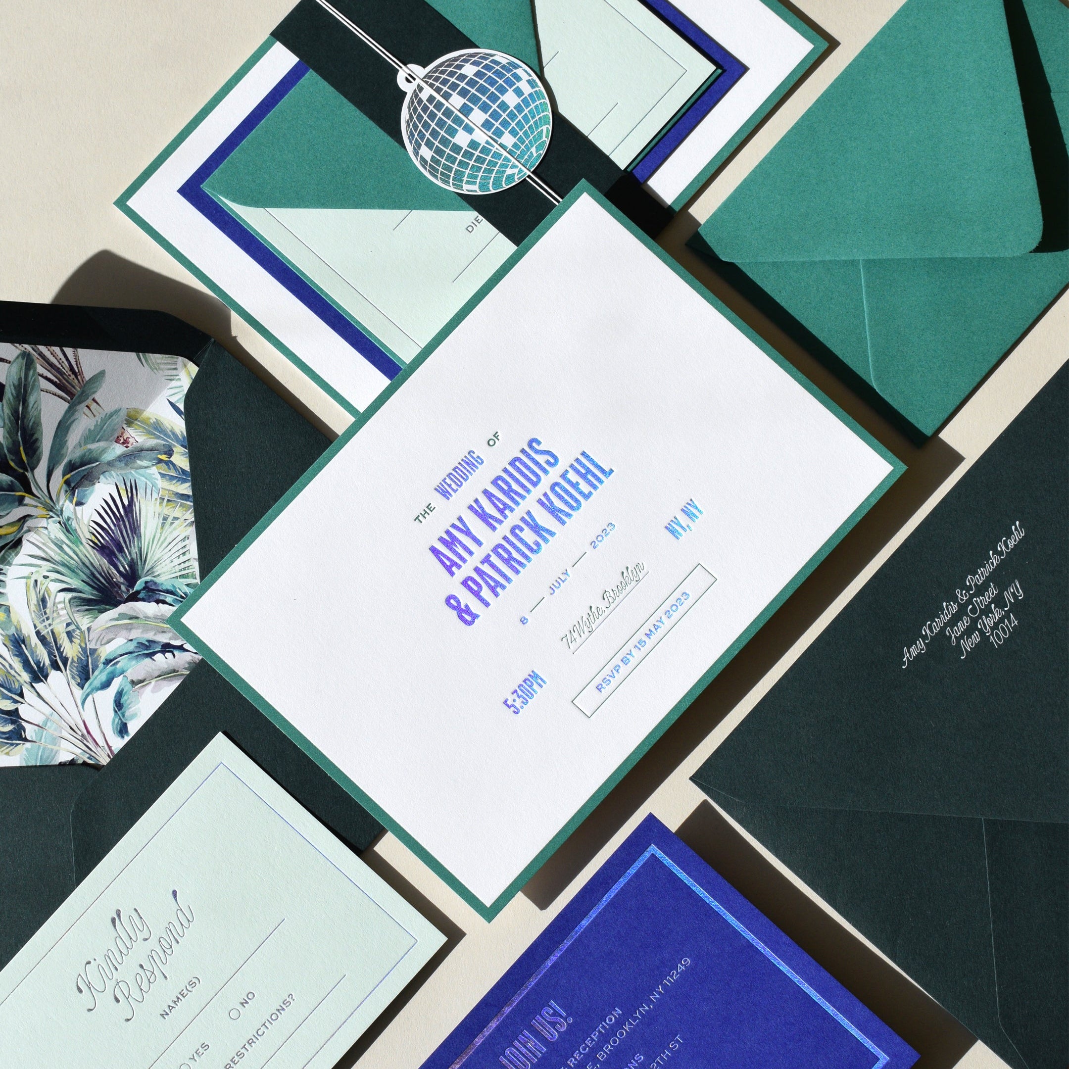 Wedding invitation set with green and blue envelopes and cards on a neutral background
