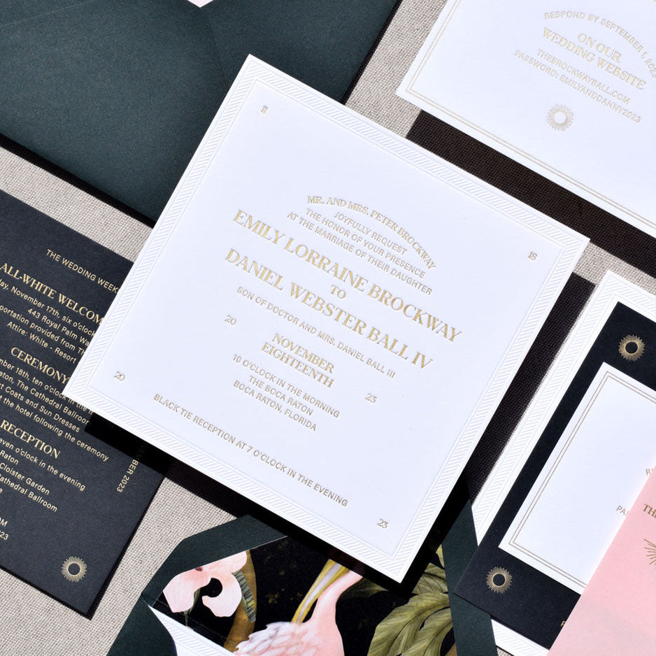 Collection of elegant wedding invitations with floral designs on a textured surface.