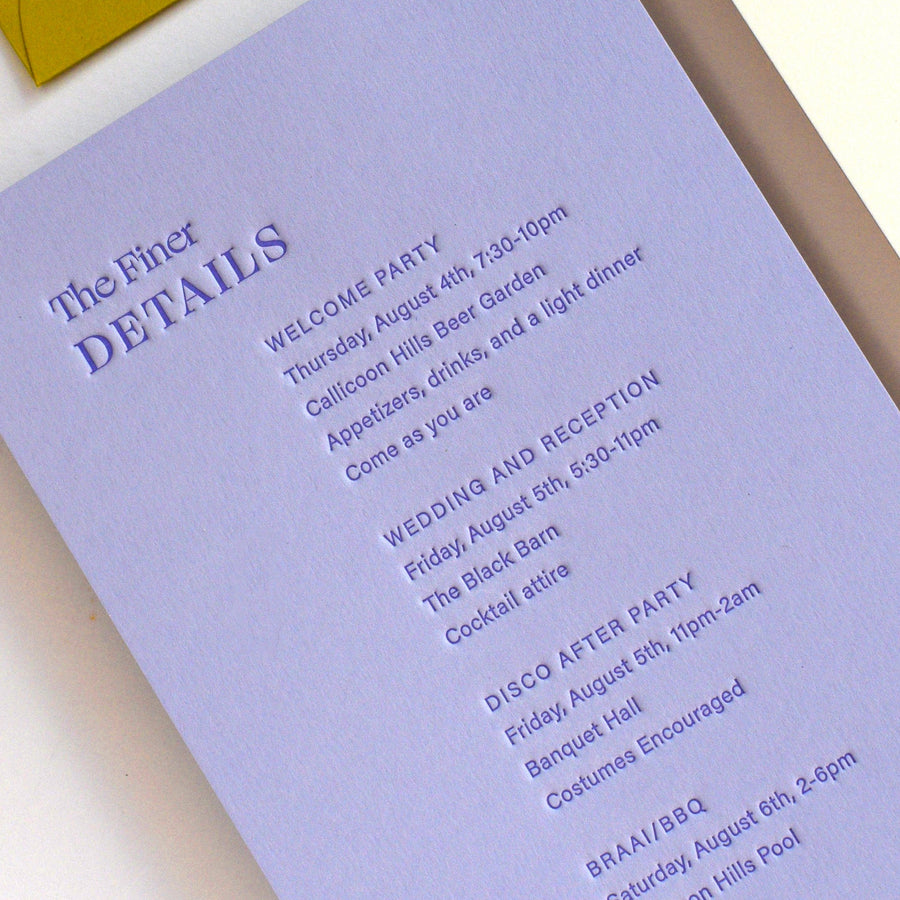 Purple event invitation card with details on a white surface