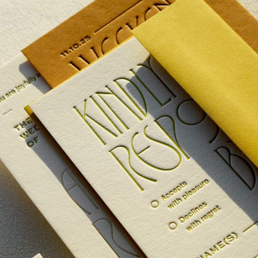 Letterpress printed card with embossed text and a yellow envelope on a textured surface.